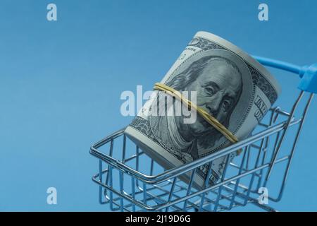 In einen Schlauch gerollte Dollars liegen in einem Einkaufskorb. Stockfoto