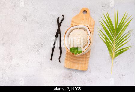 Kokoseis Aromen in der Hälfte der Kokosnuss Setup auf weißem Stein Hintergrund. Sommer und Süße Menükonzept. Stockfoto