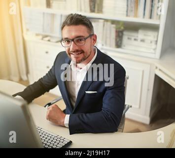 Hes der vollkommene moderne Geschäftsmann. Porträt eines Geschäftsmannes, der an seinem Computer in einem Büro arbeitet. Stockfoto