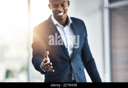 Es ist eine Freude, Sie kennenzulernen. Ein Porträt eines hübschen jungen Geschäftsmannes, der seine Hand anbot, während er in seinem modernen Büro stand. Stockfoto