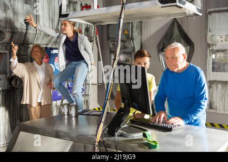 Großeltern und Enkelkinder, die sich im Fluchtzimmer mit einem Konundrommel herumtoben Stockfoto