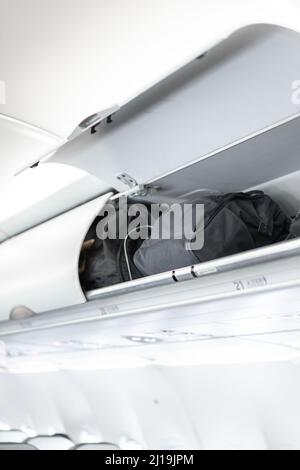 Gepäck auf dem oberen Flugzeugregal über dem Beifahrersitz Stockfoto