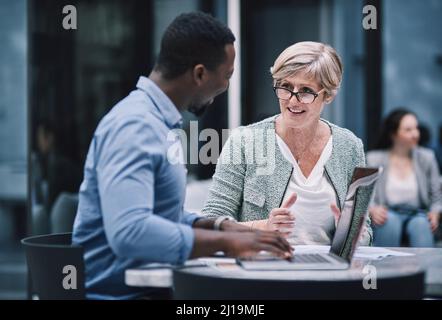 Das Team, das das Zeug dazu hat. Aufnahme eines Geschäftsmanns und einer Geschäftsfrau, die während einer Tagung in einem Kongresszentrum einen Laptop verwendet. Stockfoto