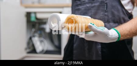 Banner austauschbar verschmutzt gebrauchter Wasserfilter zur Filtration von Umkehrosmosewasser auf Handklempner. Stockfoto