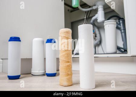 Austauschbarer verschmutzter gebrauchter Wasserfilter zur Filtration von Umkehrosmose-Wasser in der weißen Küche. Stockfoto