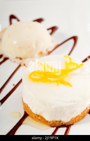 Sehr elegantes Dessert mit Zitronenmousse, Zitronenschale auf der Oberseite und Vanilleeis auf der Seite Stockfoto