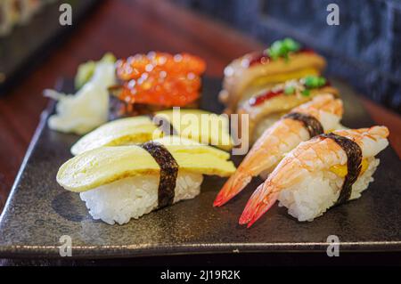 Ikura Sushi und Foie Gras, Tamago, Shrimp Nigiri auf schwarzem Teller Stockfoto