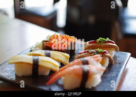 Ikura Sushi und Foie Gras, Tamago, Shrimp Nigiri auf schwarzem Teller Stockfoto