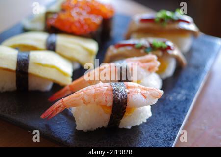 Ikura Sushi und Foie Gras, Tamago, Shrimp Nigiri auf schwarzem Teller Stockfoto