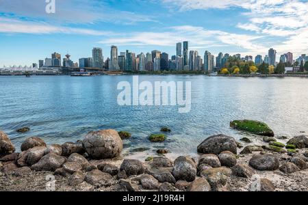 Steine an der Küste, Blick über das Meer von Hallelujah zeigen auf Skyline mit Wolkenkratzern, Stanley Park, Vancouver, British Columbia, Kanada Stockfoto