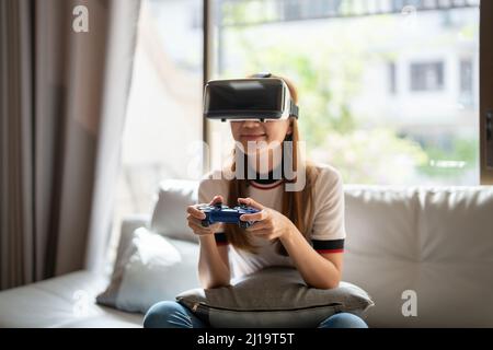 Nahaufnahme glücklich Emotion asiatische Frau spielt Videospiele mit Controller auf abstraktem Hintergrund getönt mit virtuellen Brillen Stockfoto