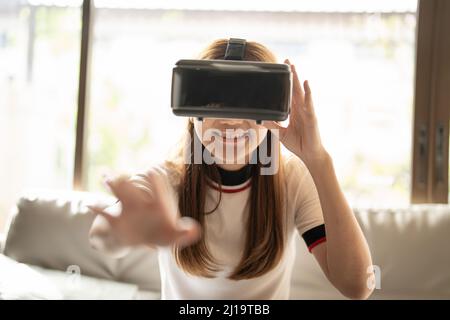 Begeistern asiatische Frau spielen Online-Spiel mit vr Brille und Controller bei ihr zu Hause Stockfoto