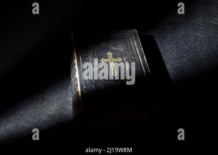 Alte Bibel, Buch auf schwarzem Hintergrund, grasendes Licht Stockfoto