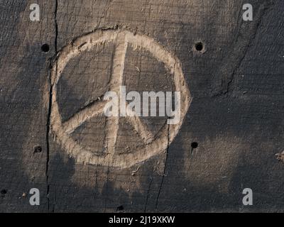 Das Friedenssymbol in Holz mit Meißeln geschnitzt. Friedenskonzept, globale Solidarität Stockfoto