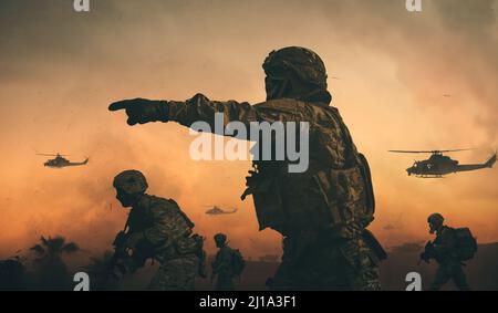 Militärkräfte & Hubschrauber zwischen Rauch und Staub auf dem Schlachtfeld Stockfoto