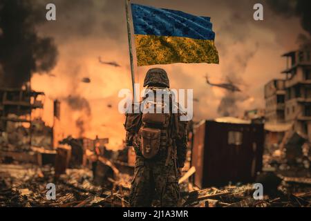 Ein ukrainischer Soldat steht mit ukrainischer Flagge in der Hand und schaut auf die zerstörte Stadt Stockfoto