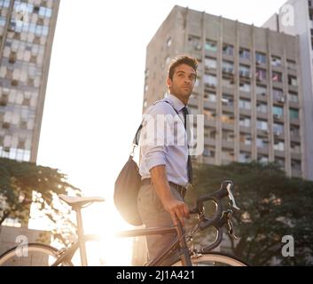 Seine CO2-Bilanz so gering wie möglich zu halten. Aufnahme eines Geschäftsmannes, der mit seinem Fahrrad zur Arbeit pendelt. Stockfoto