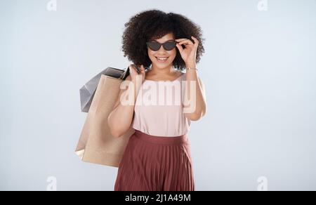 So sieht ein zufriedener Kunde aus. Studioporträt einer attraktiven jungen Frau, die eine Reihe von Einkaufstaschen trägt. Stockfoto