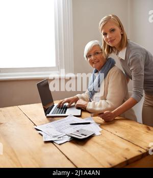 Eine Hand mit Grandmas Steuererklärungen verleihen. Eine Enkelin hilft ihrer Großmutter mit ihrem Budget. Stockfoto