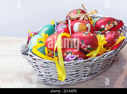 Ostereier aus Holz mit floralen Ornamenten in einem Korbkorb. Stockfoto