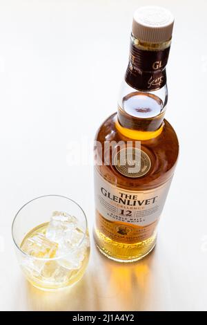 Moskau, Russland - 20. März 2022: Glas- und geschlossene Flasche des 12 Jahre alten Glenlivet Single Malt Scotch Whisky auf hellem Tisch. Glenlivet Destillerie war f Stockfoto