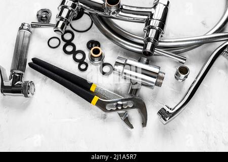 Ansicht von Schraubenschlüssel und zerlegtem Duschhahn auf Betonplatte Stockfoto
