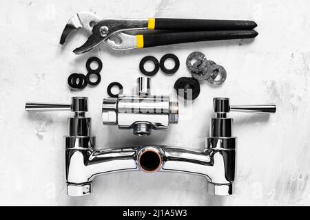 Sanitär Hintergrund - Draufsicht auf Schlüssel, Dichtungen, zerlegtes Dusche Wasserhahn Ventil, Umleiter auf Betonplatte Stockfoto
