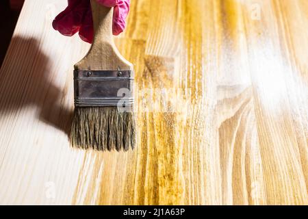 Holzbrett ist mit Holzfleck durch Pinsel aus nächster Nähe zu Hause bedeckt Stockfoto