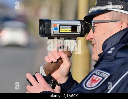 Seelow, Deutschland. 24. März 2022. Peter Gnida, Polizeiinspektor, steht mit einer Laserpistole vor einer Schule und misst die Geschwindigkeit von Fahrzeugen in einer 30-Zone. Auch die Polizei in Brandenburg nimmt im Rahmen der europaweiten Kontrollwoche zu Geschwindigkeits- und Aggressionsvergehen am diesjährigen Speed-Marathon Teil. An diesem Donnerstag werden landesweite Geschwindigkeitskontrollen durchgeführt. Quelle: Patrick Pleul/dpa-Zentralbild/dpa/Alamy Live News Stockfoto