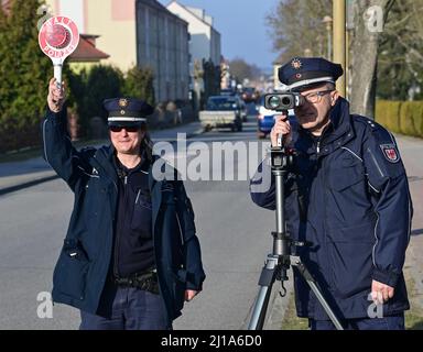 Seelow, Deutschland. 24. März 2022. Claudia Pirke, Polizeipräsident, und Peter Gnida, Polizeipräsident, stehen mit einem Lasergewehr vor einer Schule und messen die Geschwindigkeit der Fahrzeuge in einer 30-km-Zone. Auch die Polizei in Brandenburg nimmt in diesem Jahr im Rahmen der europaweiten Kontrollwoche zu Geschwindigkeits- und Aggressionsvergehen am Speed Marathon Teil. An diesem Donnerstag werden landesweite Geschwindigkeitskontrollen durchgeführt. Quelle: Patrick Pleul/dpa-Zentralbild/dpa/Alamy Live News Stockfoto