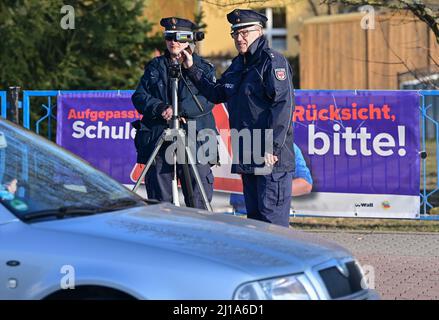 Seelow, Deutschland. 24. März 2022. Claudia Pirke, Polizeipräsident, und Peter Gnida, Polizeipräsident, stehen mit einem Lasergewehr vor einer Schule und messen die Geschwindigkeit der Fahrzeuge in einer 30-km-Zone. Auch die Polizei in Brandenburg nimmt in diesem Jahr im Rahmen der europaweiten Kontrollwoche zu Geschwindigkeits- und Aggressionsvergehen am Speed Marathon Teil. An diesem Donnerstag werden landesweite Geschwindigkeitskontrollen durchgeführt. Quelle: Patrick Pleul/dpa-Zentralbild/dpa/Alamy Live News Stockfoto