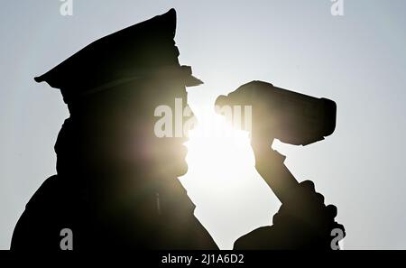 Seelow, Deutschland. 24. März 2022. Peter Gnida, Polizeiinspektor, steht mit einer Laserpistole vor einer Schule und misst die Geschwindigkeit von Fahrzeugen in einer 30-Zone. Auch die Polizei in Brandenburg nimmt im Rahmen der europaweiten Kontrollwoche zu Geschwindigkeits- und Aggressionsvergehen am diesjährigen Speed-Marathon Teil. An diesem Donnerstag werden landesweite Geschwindigkeitskontrollen durchgeführt. Quelle: Patrick Pleul/dpa-Zentralbild/dpa/Alamy Live News Stockfoto