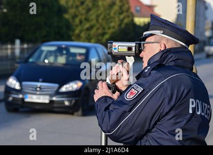 Seelow, Deutschland. 24. März 2022. Peter Gnida, Polizeiinspektor, steht mit einer Laserpistole vor einer Schule und misst die Geschwindigkeit von Fahrzeugen in einer 30-Zone. Auch die Polizei in Brandenburg nimmt im Rahmen der europaweiten Kontrollwoche zu Geschwindigkeits- und Aggressionsvergehen am diesjährigen Speed-Marathon Teil. An diesem Donnerstag werden landesweite Geschwindigkeitskontrollen durchgeführt. Quelle: Patrick Pleul/dpa-Zentralbild/dpa/Alamy Live News Stockfoto