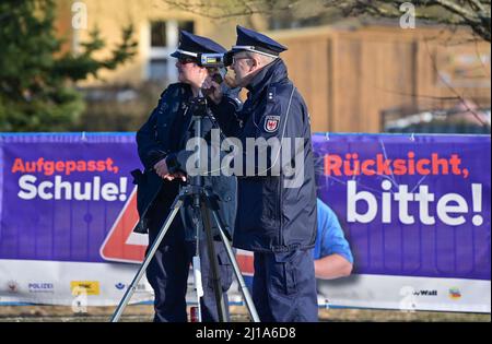 Seelow, Deutschland. 24. März 2022. Claudia Pirke, Polizeipräsident, und Peter Gnida, Polizeipräsident, stehen mit einem Lasergewehr vor einer Schule und messen die Geschwindigkeit der Fahrzeuge in einer 30-km-Zone. Auch die Polizei in Brandenburg nimmt in diesem Jahr im Rahmen der europaweiten Kontrollwoche zu Geschwindigkeits- und Aggressionsvergehen am Speed Marathon Teil. An diesem Donnerstag werden landesweite Geschwindigkeitskontrollen durchgeführt. Quelle: Patrick Pleul/dpa-Zentralbild/dpa/Alamy Live News Stockfoto