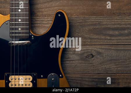 Vintage schwarze und gelbe E-Gitarre auf Holzhintergrund Stockfoto