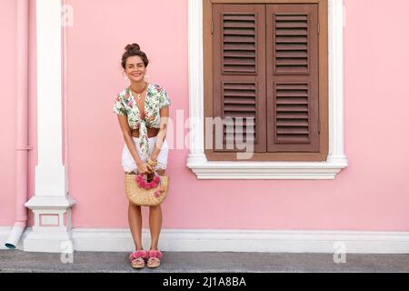 Schöne und stilvolle Frau posiert neben dem Haus mit einer rosa Wand Stockfoto