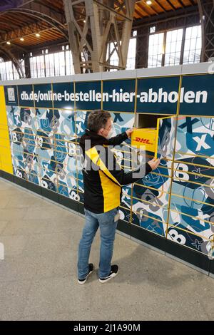 Leipzig, Deutschland. 24. März 2022. Ein Mitarbeiter der Deutschen Post arbeitet während einer Präsentation am Hauptbahnhof an einer Packstation. Deutsche Bahn und Deutsche Post starten eine Kooperation zu Packstationen. Quelle: Sebastian Willnow/dpa-Zentralbild/dpa/Alamy Live News Stockfoto