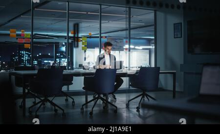 Betont kreativer Geschäftsmann denken; CEO arbeitet an Laptop-Computer in Big City Office spät am Abend. Geschäftsmann, der sich auf ein Meeting vorbereitet Stockfoto