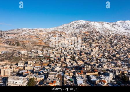 Hermon Bergrücken bedeckt mit Schnee im Winter 2022, mit den Stadthäusern von Majd al Shams. Stockfoto