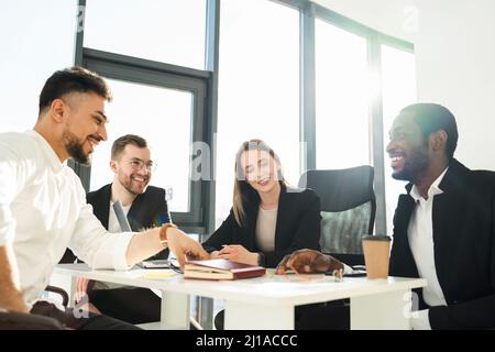 Gruppe von mehrrassischen Firmenmitarbeitern in formeller Kleidung, die eine Sitzung in einem sonnigen Büro haben Stockfoto