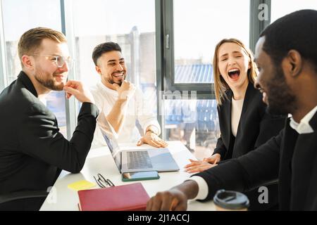 Gruppe lachender Mitarbeiter des Unternehmens bei einer Besprechung im Büro Stockfoto