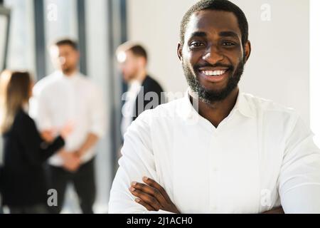 Porträt eines fröhlichen schwarzen Firmenmitarbeiters mit gekreuzten Armen Stockfoto