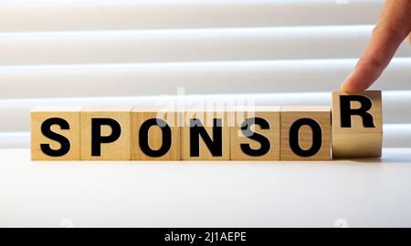 Nahaufnahme der Hand eines Geschäftsmannes arrangieren kleine Holzklötze auf der Tabelle für Business Sponsor und Stipendium Konzept. Stockfoto