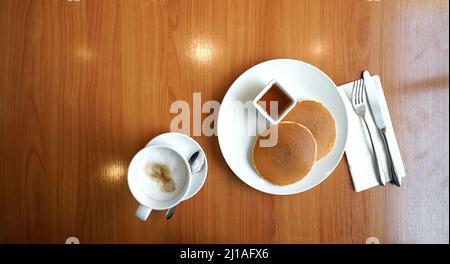 Zwei Pfannkuchen, serviert mit Ahornsirup auf einem Holztisch. Draufsicht. Stockfoto