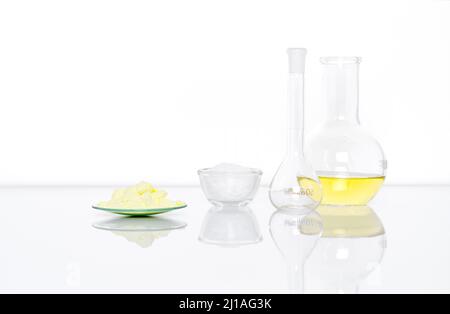 Schwefelpulver im chemischen Uhrenglas Stellen Sie neben der weißen Flockenchemikalie in Glasbehälter, Volumetrische Flasche und Aluminiumchlorid-Flüssigkeit in flacher Bo Stockfoto