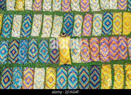 Narayanganj, Dhaka, Bangladesch. 24. März 2022. Tausende von bunten Tüchern werden zum Trocknen unter der heißen Sonne ausgelegt. Nachdem der Stoff gefärbt wurde, werden sie auf einem etwa 10.000 Quadratfuß großen Feld im Batik Village in Narayanganj, Bangladesch, verteilt.Sobald sie trocken sind - was normalerweise vier Stunden dauert - werden sie zu Kleidung gemacht, die weltweit verkauft wird. (Bild: © Mustasinur Rahman Alvi/ZUMA Press Wire) Bild: ZUMA Press, Inc./Alamy Live News Stockfoto