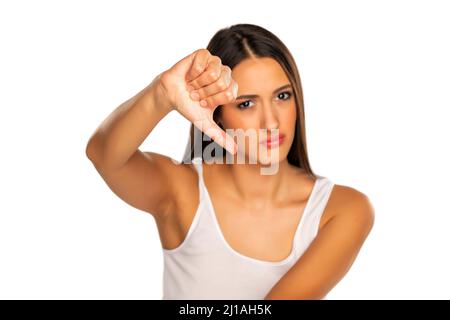 Verärgerte Frau, die die Daumen-nach-unten-Geste auf weißem Hintergrund nicht mag Stockfoto