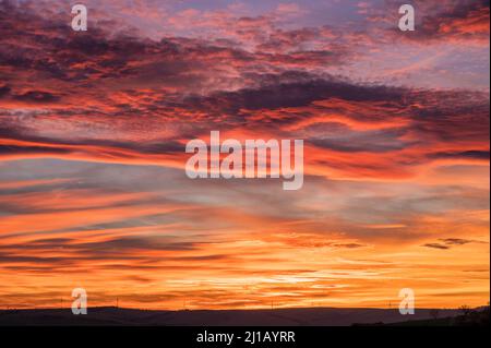 Intensiv gefärbter wolkiger Himmel bei einem romantischen Sonnenuntergang Stockfoto