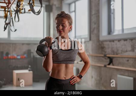 Sportliche Sportlerin beim Heben der Kugelhantel im Fitnessstudio Stockfoto