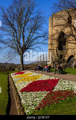 Menschen sitzen entspannt Sonne genießen (helle Border Blumen, alten Turm halten Ruinen, blauer Himmel) - Knaresborough Castle, North Yorkshire, England, Großbritannien. Stockfoto